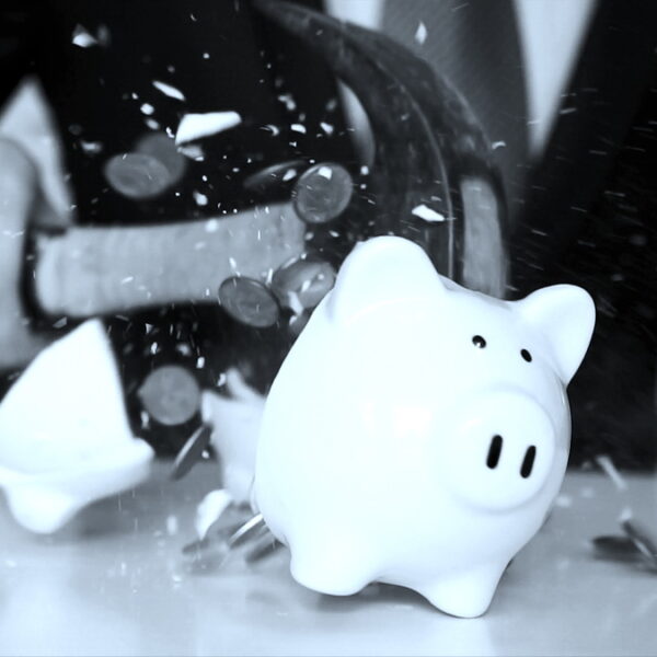 Close-up of businessman using a hammer to smash plenty of coins inside piggybank into pieces as he needs emergency money - using money in financial crisis concept. Close-up of businessman using a hammer to smash plenty of coins inside piggybank into pieces as he needs emergency money - using money in financial crisis concept