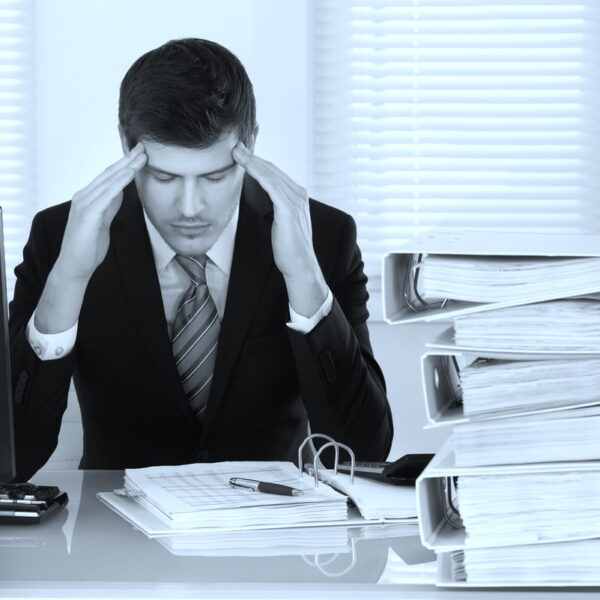 Businessman Suffering From Headache Businessman Suffering From Headache With Invoice On Desk